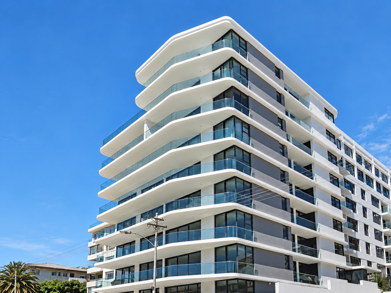 A modern multi-story apartment building featuring contemporary architecture with clean lines and extensive glass balcony balustrades.