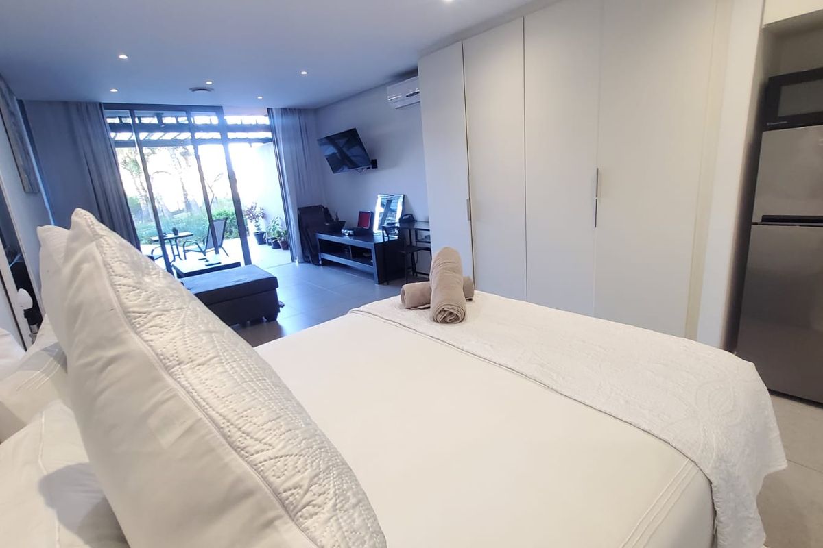 Spacious bedroom featuring built-in cupboards, tiled flooring, recessed lighting, and direct access to an outdoor patio area through sliding glass doors.