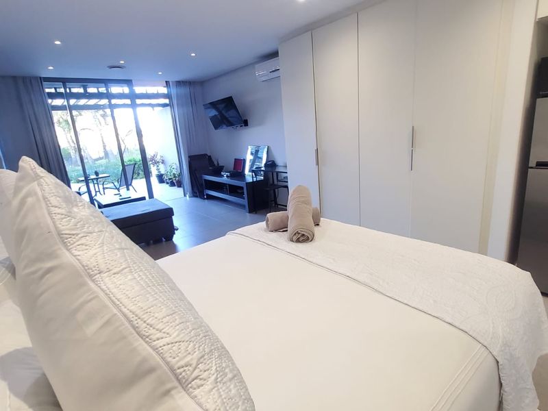 Spacious bedroom featuring built-in cupboards, tiled flooring, recessed lighting, and direct access to an outdoor patio area through sliding glass doors.