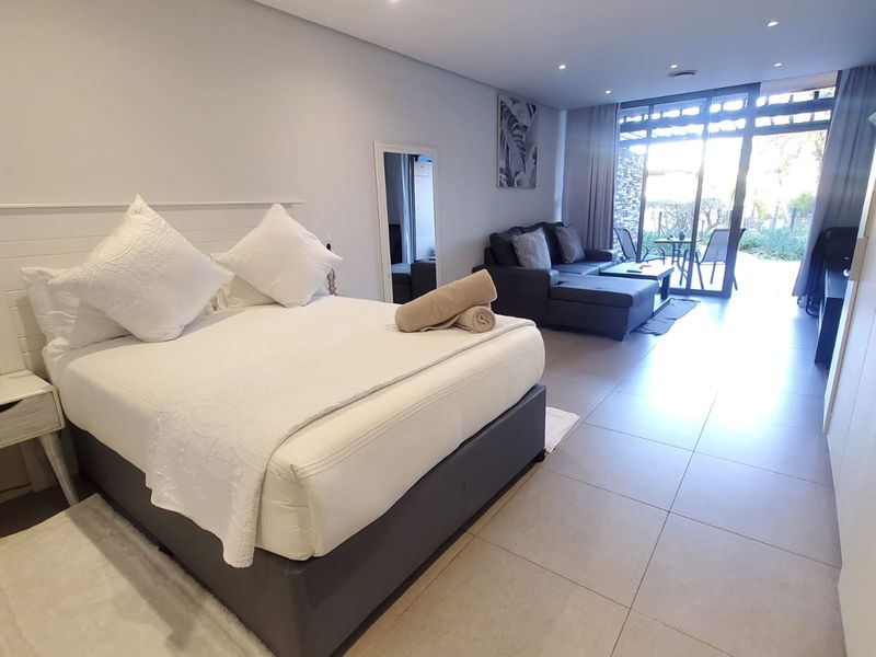 Spacious bedroom featuring tiled flooring, recessed lighting, and large sliding glass doors that open onto a private outdoor patio area.