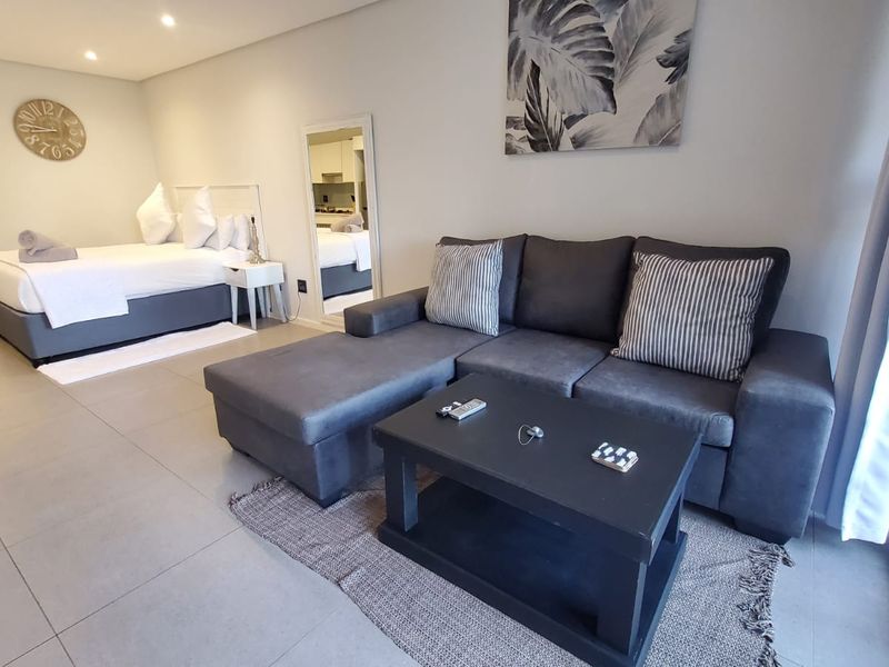 An open-plan studio apartment featuring tiled flooring, recessed lighting, and a sliding door leading to an outdoor area.