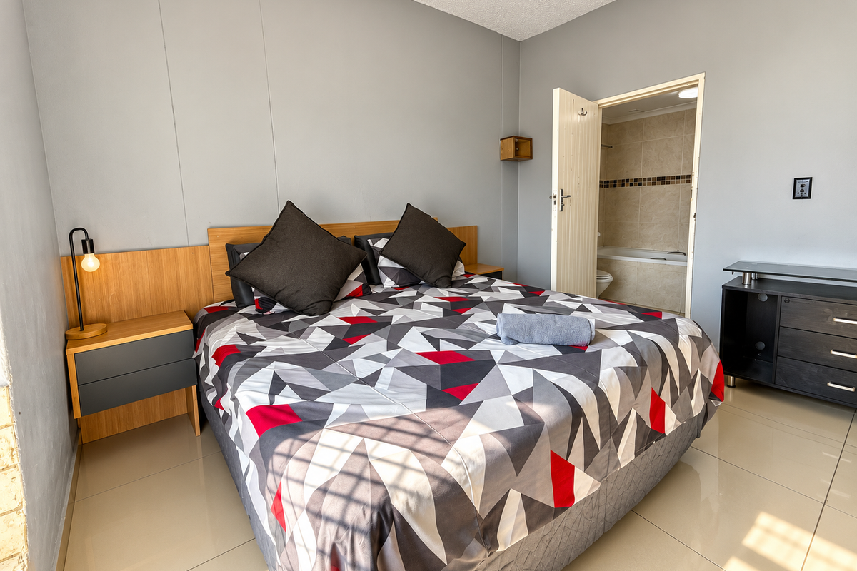 A well-maintained bedroom featuring tiled flooring, a built-in headboard, and direct access to an en-suite bathroom.