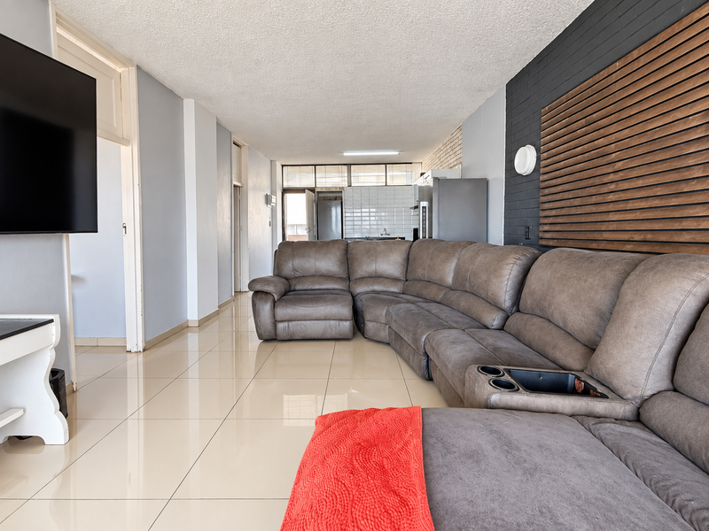 Open plan living area featuring large format floor tiles, a timber slat feature wall, and an integrated kitchen space with tiled backsplash.