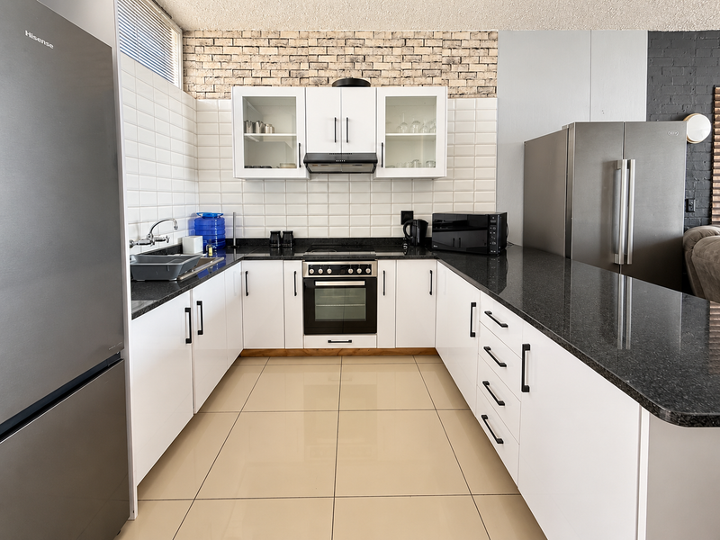 Modern kitchen featuring white cabinetry, dark granite countertops, tiled backsplash, and integrated appliances, offering a clean and functional workspace.