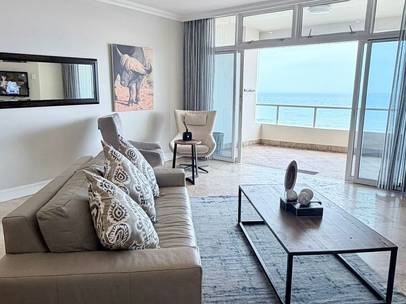 Spacious living room featuring tiled floors, dual ceiling fans, and large sliding glass doors opening onto a balcony with ocean views.