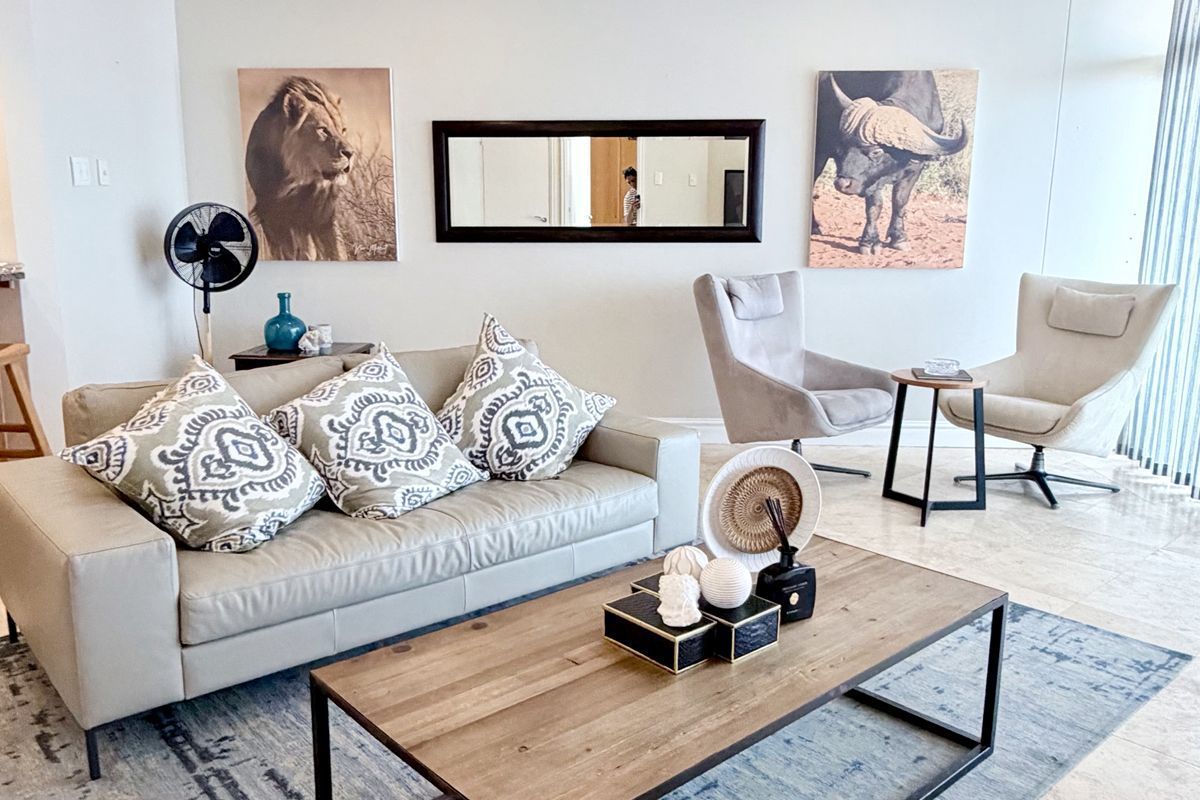 A bright and well-maintained living room featuring neutral tiled flooring, recessed downlights, and dual ceiling fans, creating a comfortable and inviting atmosphere.