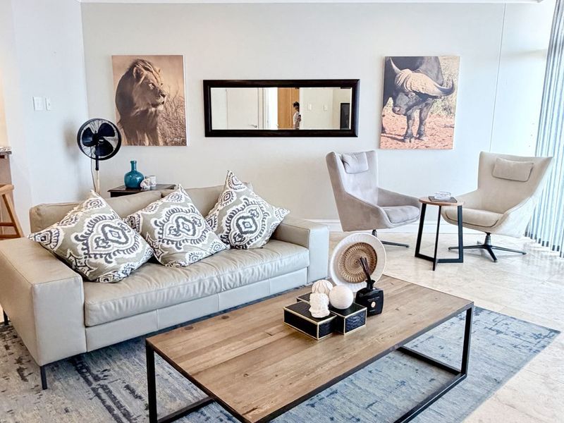 A bright and well-maintained living room featuring neutral tiled flooring, recessed downlights, and dual ceiling fans, creating a comfortable and inviting atmosphere.