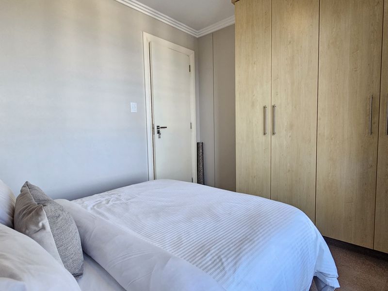 A well-maintained bedroom featuring neutral wall finishes, coving, and a large built-in wooden wardrobe providing ample storage space.