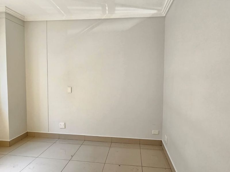 A clean, empty bedroom featuring neutral tiled flooring, white walls, and an aluminium-framed window, providing a blank canvas for personalization.