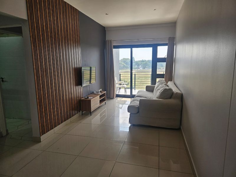 A modern living room featuring a decorative slatted wood accent wall, large format floor tiles, and a sliding door leading to an outdoor balcony.