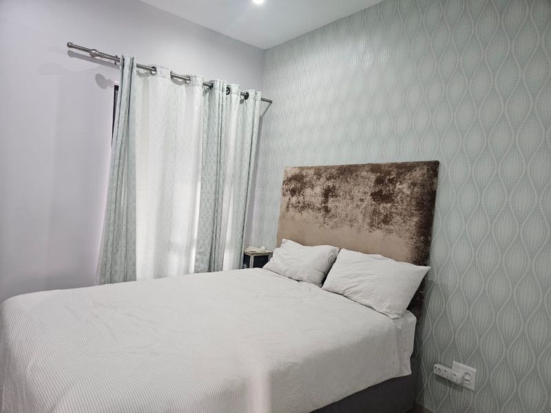 A well-maintained bedroom featuring patterned wallpaper, a curtain rod, and a functional electrical outlet.
