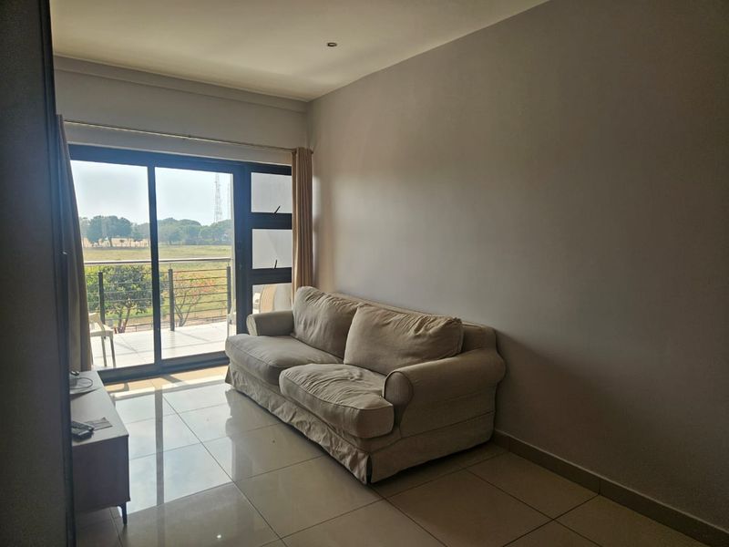 A living room featuring large sliding glass doors that open onto a balcony, providing natural light and scenic views.