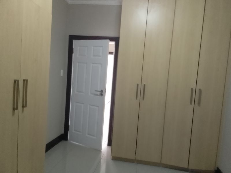 A bedroom featuring light wood-finish built-in cupboards and tiled flooring, providing ample storage space.