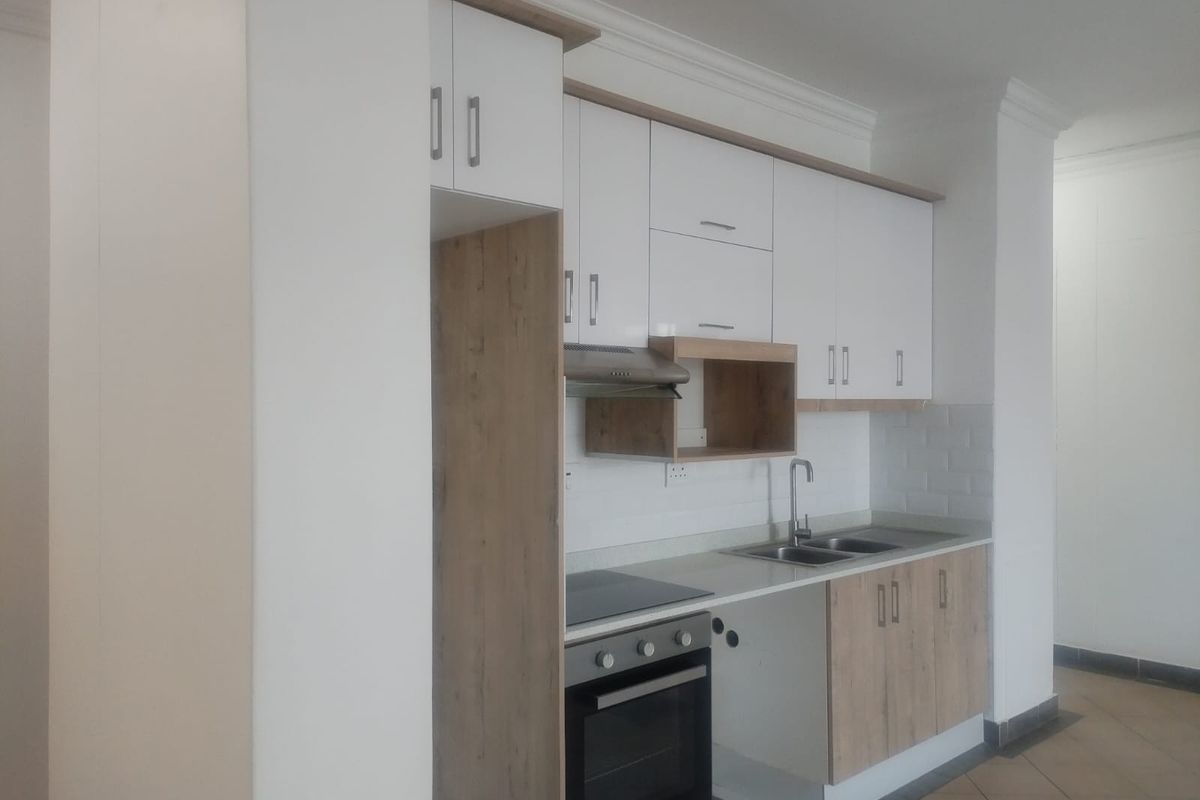 Modern kitchen featuring white and wood-tone cabinetry, built-in oven and hob, stainless steel sink, and a clean subway tile backsplash.