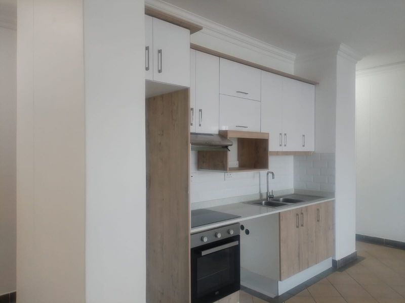 Modern kitchen featuring white and wood-tone cabinetry, built-in oven and hob, stainless steel sink, and a clean subway tile backsplash.