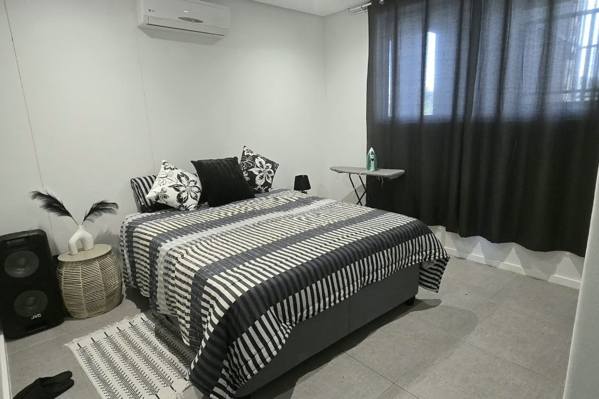 A well-maintained bedroom featuring tiled flooring and a wall-mounted split-system air conditioner.