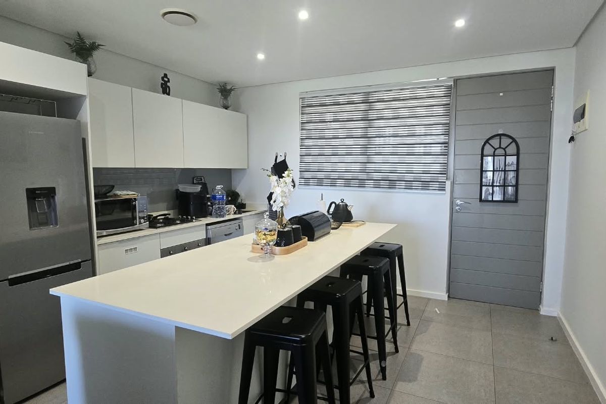 Modern kitchen featuring a central island with quartz countertops, sleek white cabinetry, recessed lighting, and tiled flooring.