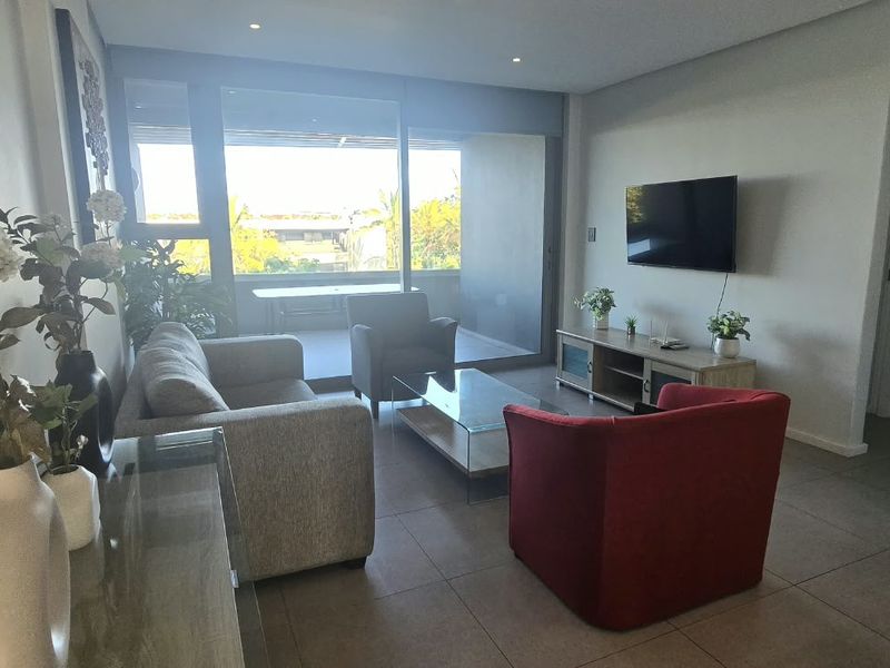 Modern living room featuring tiled floors, recessed lighting, and large sliding glass doors providing access to an outdoor balcony area.