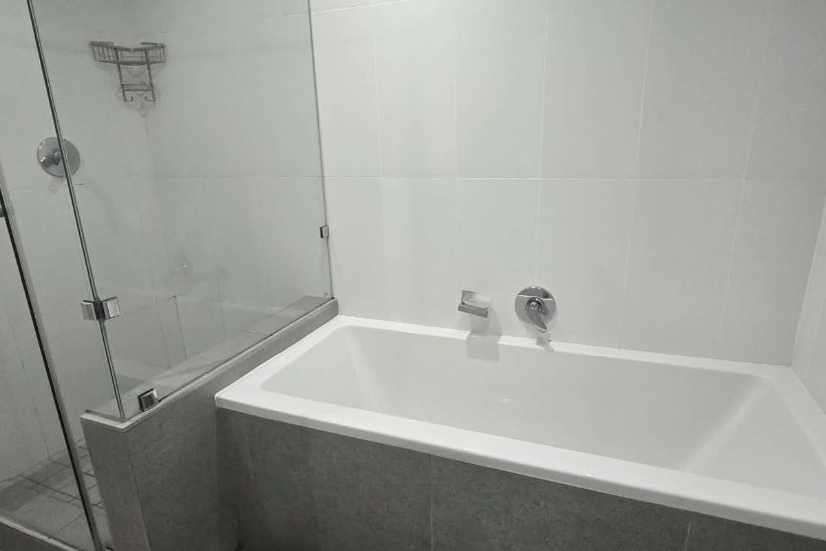 A clean, modern bathroom featuring a built-in bathtub and a separate glass-enclosed shower with neutral wall tiling.