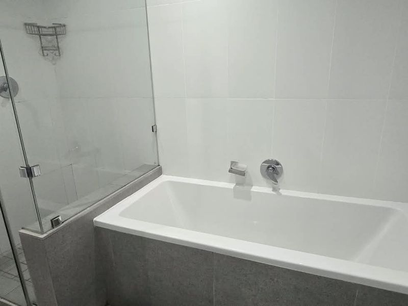 A clean, modern bathroom featuring a built-in bathtub and a separate glass-enclosed shower with neutral wall tiling.