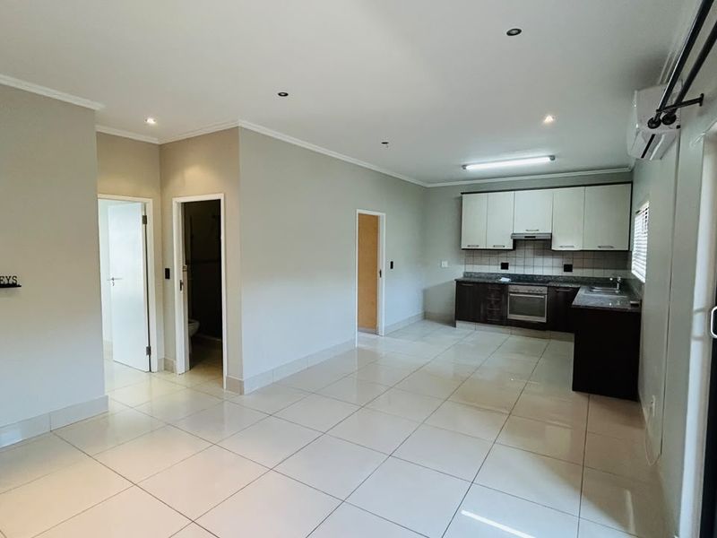 Spacious open-plan living area featuring tiled floors, recessed lighting, and a modern kitchen with built-in cabinetry, granite countertops, and integrated appliances.