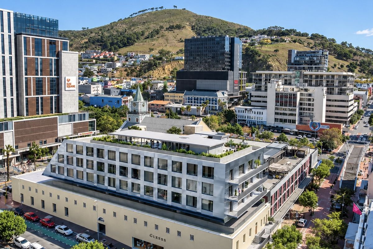 Aerial view of a modern apartment building featuring a rooftop terrace and balconies, situated in a vibrant urban neighborhood.