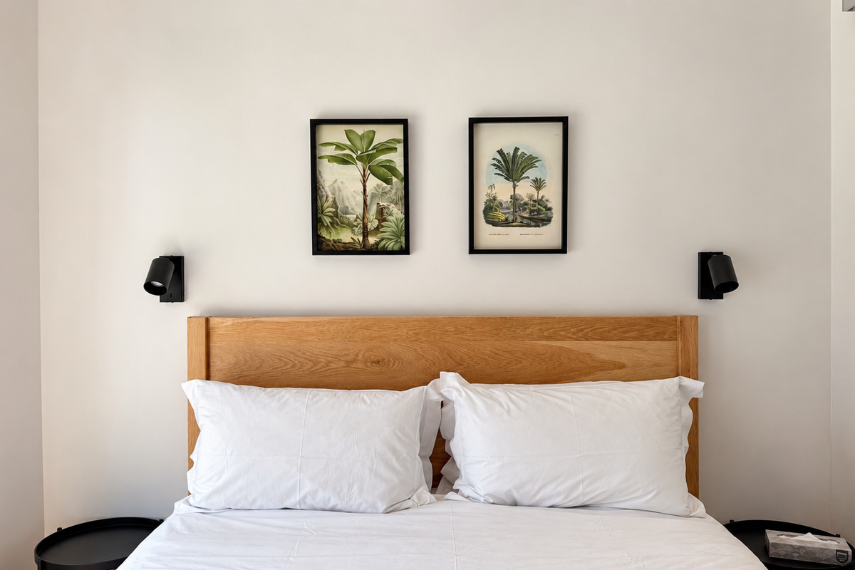 A clean and modern bedroom featuring wall-mounted reading lights and a neutral aesthetic.