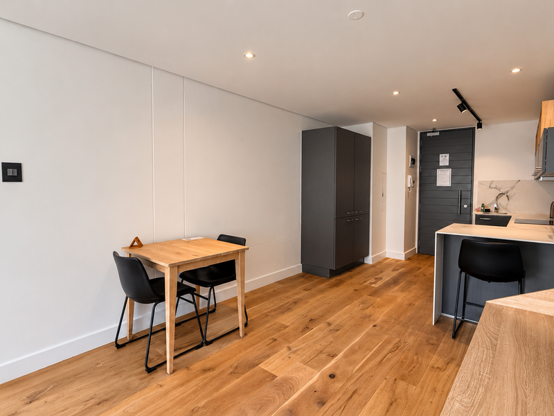 Modern open-plan apartment featuring hardwood flooring, a sleek kitchen with built-in cabinetry, stone backsplash, and a functional island layout.