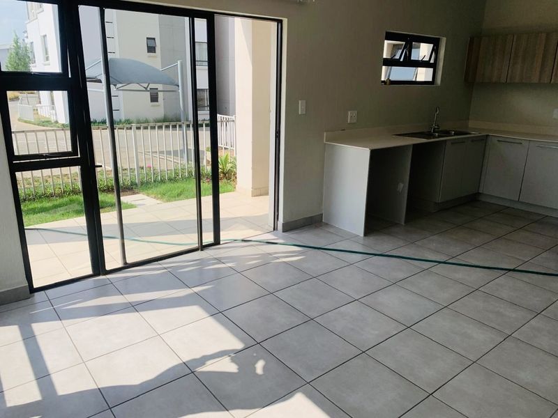 Open plan kitchen and living area featuring tiled floors and direct access to a patio through large sliding glass doors.