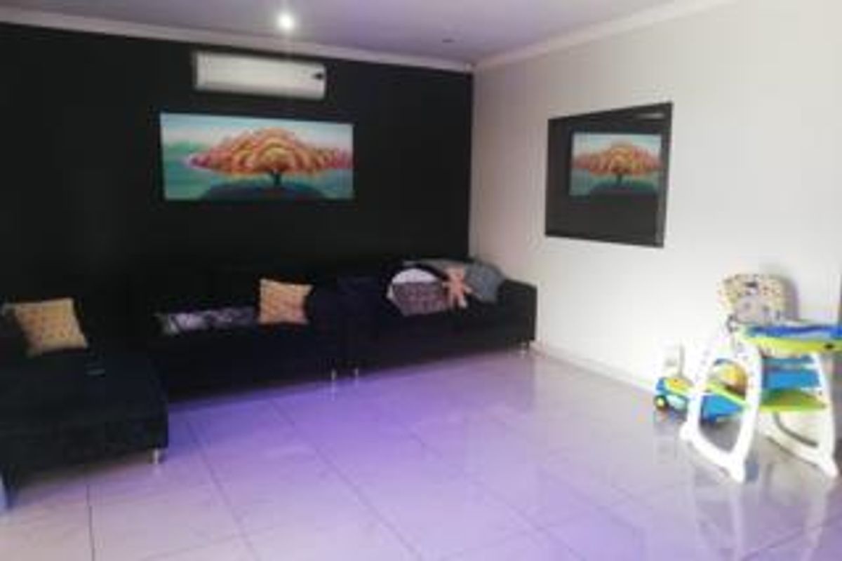 A living room featuring tiled flooring, a split-system air conditioner, and a recessed wall niche, providing a functional and open living space.