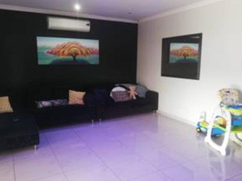 A living room featuring tiled flooring, a split-system air conditioner, and a recessed wall niche, providing a functional and open living space.