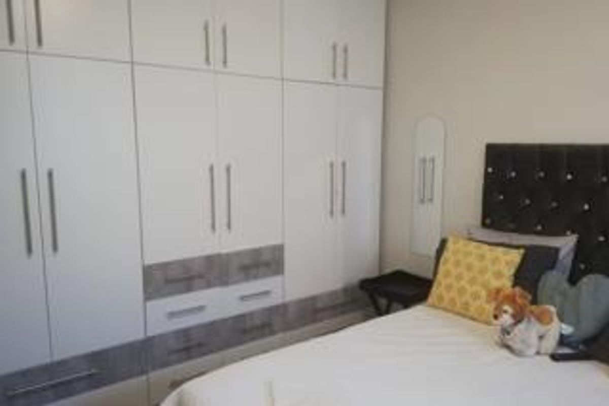 A bedroom featuring extensive white built-in cupboards with integrated drawers and modern hardware.