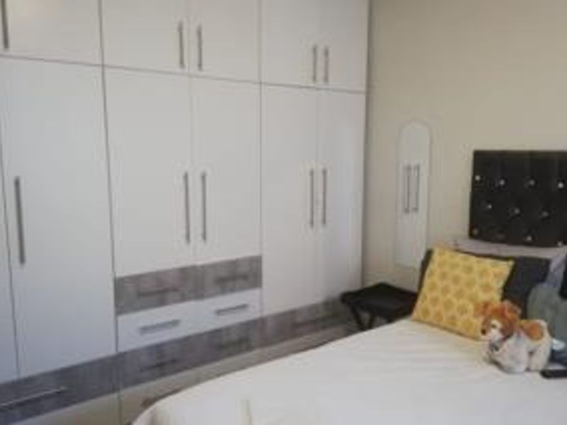 A bedroom featuring extensive white built-in cupboards with integrated drawers and modern hardware.