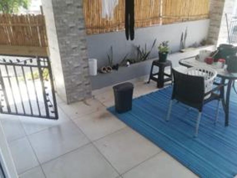 A covered patio area featuring tiled flooring, a stone-clad pillar, and a built-in planter box, providing a functional outdoor space.