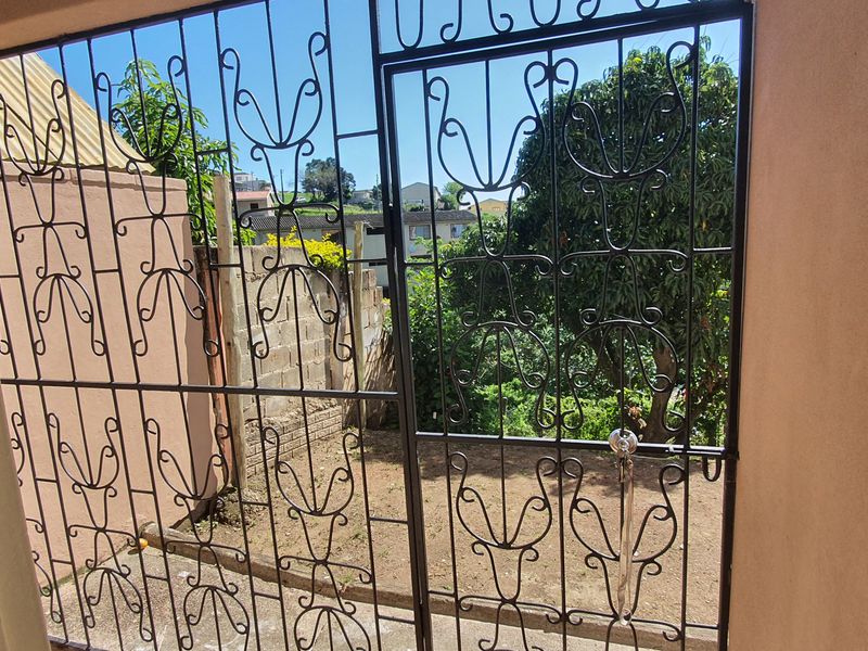 A covered patio area featuring a decorative metal security gate and access to a small rear garden space.