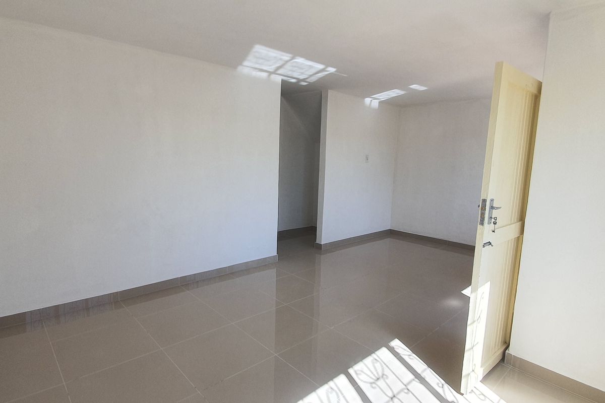 A bright, empty bedroom featuring neutral tiled flooring and clean white walls, providing a versatile blank canvas for interior design.