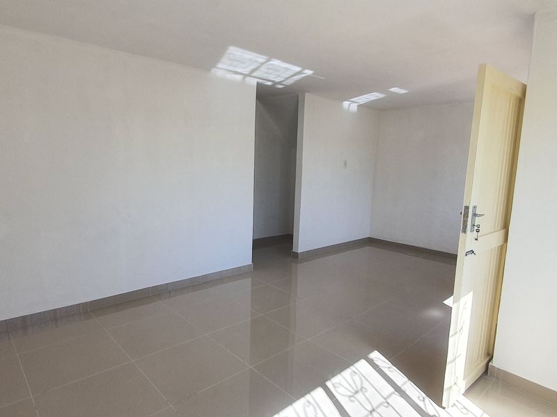 A bright, empty bedroom featuring neutral tiled flooring and clean white walls, providing a versatile blank canvas for interior design.