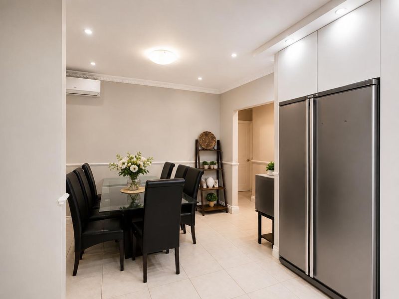 A well-maintained dining area featuring tiled flooring, recessed lighting, ceiling cornices, and built-in cabinetry, providing a clean and functional space.