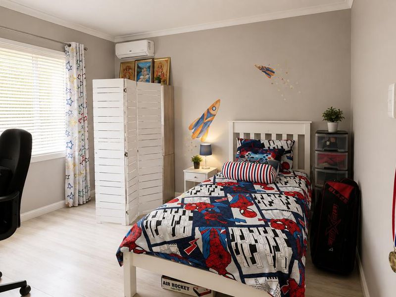 A well-maintained bedroom featuring light-toned laminate flooring, neutral wall paint, and a wall-mounted split-system air conditioning unit.