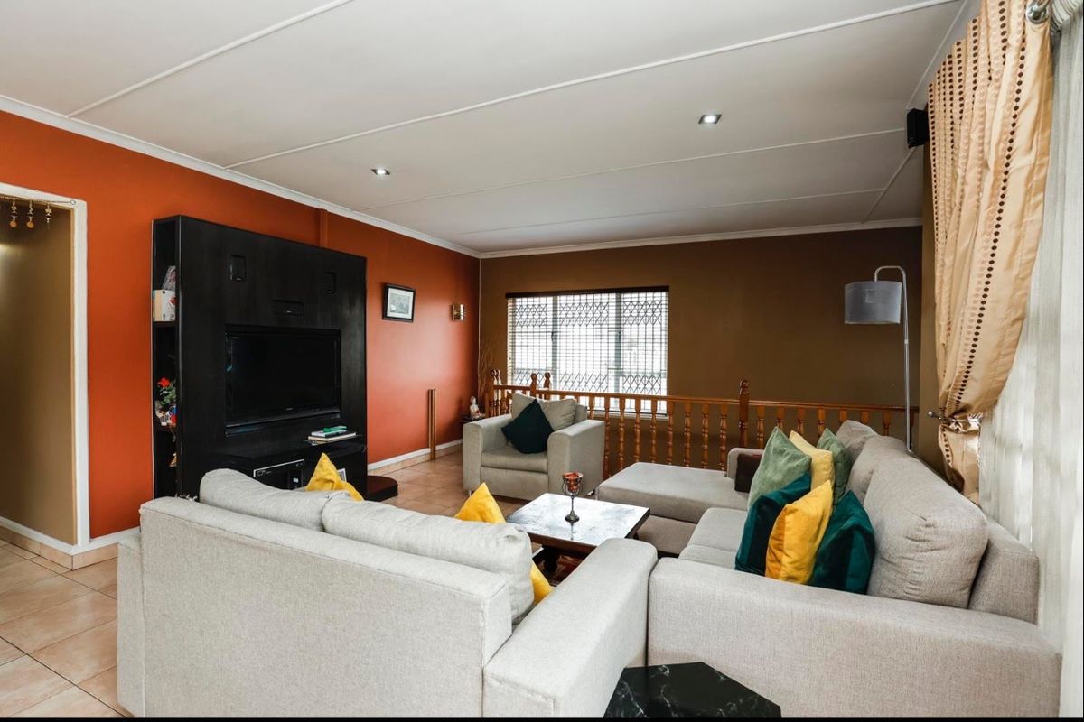 Spacious living room featuring tiled flooring, recessed downlighting, and a wooden balustrade overlooking the lower level.