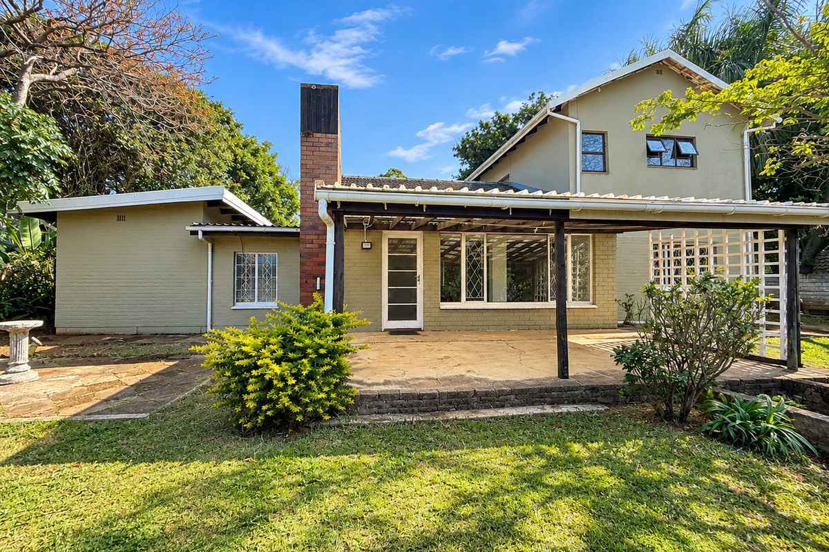 Rear view of the house featuring a covered patio area with a brick chimney, paved flooring, and a timber pergola structure.