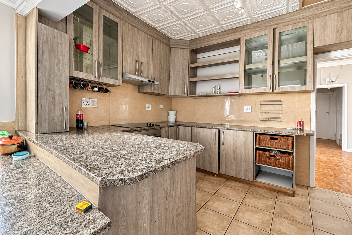 A functional kitchen featuring wood-look laminate cabinetry, granite-style countertops, ceramic tile flooring, and decorative ceiling tiles, with some minor maintenance required.