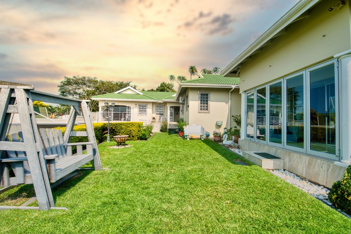 A well-maintained rear garden featuring a manicured lawn, tiled patio area, and modern bi-fold doors providing seamless indoor-outdoor flow.