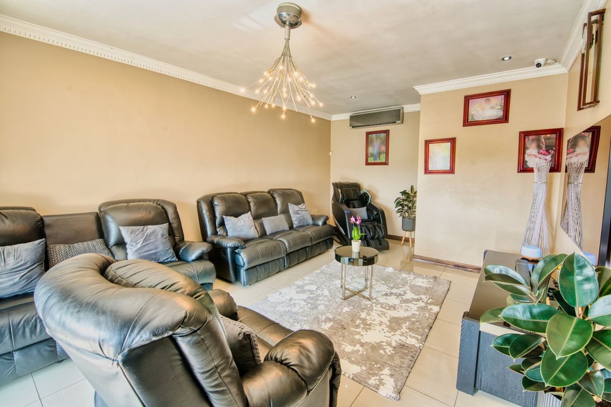 A comfortable living room featuring tiled flooring, crown molding, and a split-system air conditioning unit for climate control.