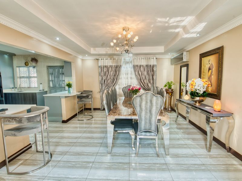 Spacious open-plan dining and kitchen area featuring polished porcelain tiles, modern recessed ceiling lighting, and a functional breakfast bar layout.