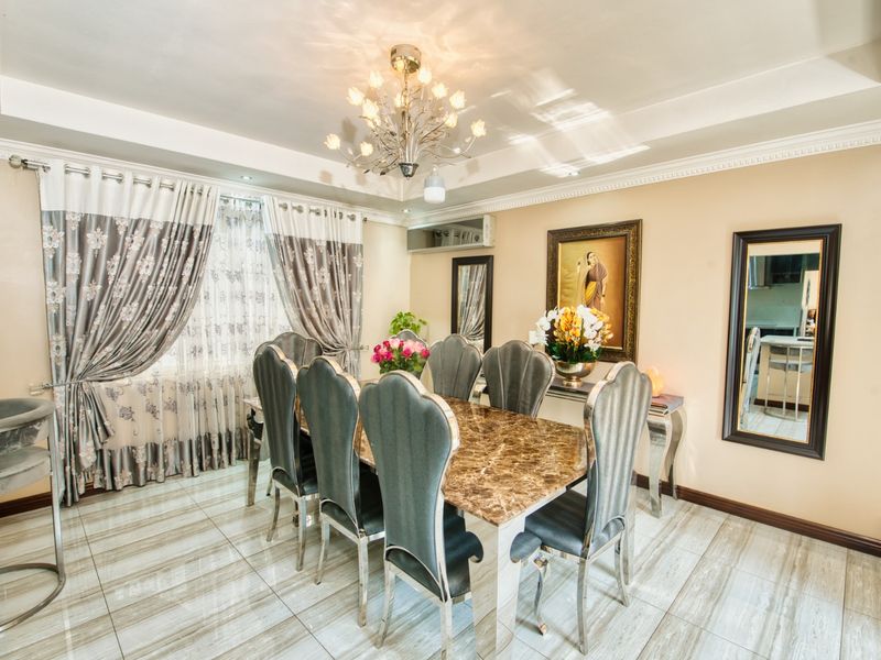 A formal dining room featuring polished tiled flooring, decorative crown molding, and a central chandelier, creating an elegant space for entertaining.