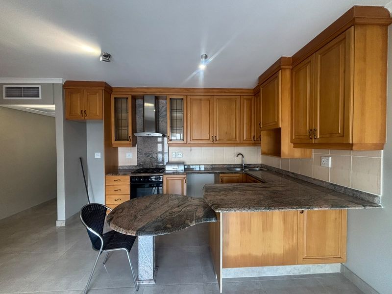 A functional kitchen featuring wooden cabinetry, granite countertops, a built-in oven, and a breakfast nook, offering a practical layout for daily use.