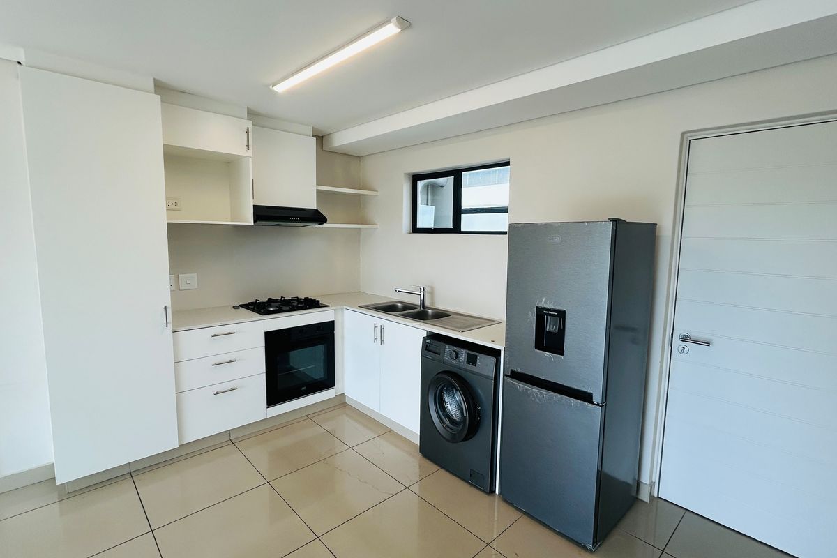 Modern kitchen featuring white cabinetry, gas hob, built-in oven, extractor fan, and tiled flooring in a clean, functional layout.
