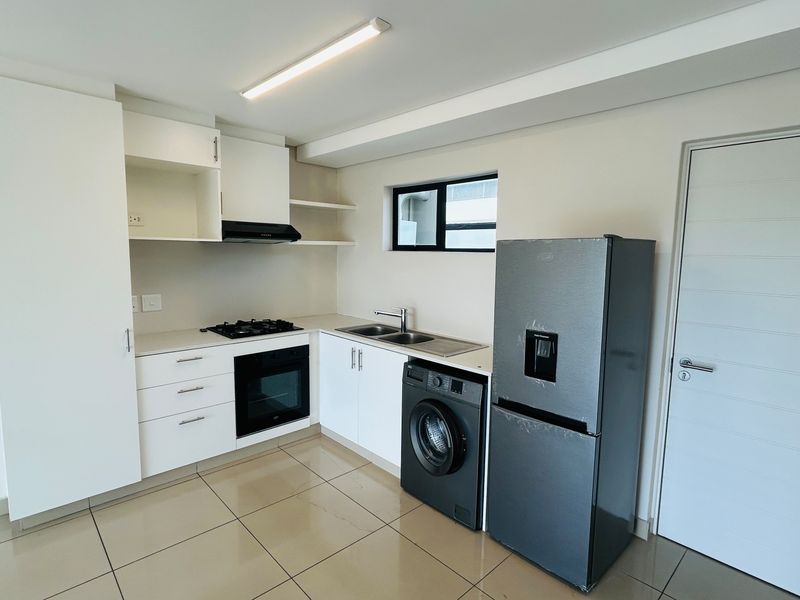 Modern kitchen featuring white cabinetry, gas hob, built-in oven, extractor fan, and tiled flooring in a clean, functional layout.