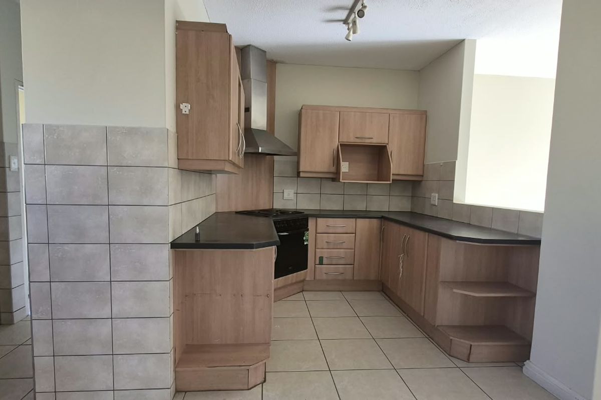 A functional kitchen featuring laminate cabinetry, built-in oven, extractor fan, and tiled flooring, requiring minor repairs and cosmetic updates.